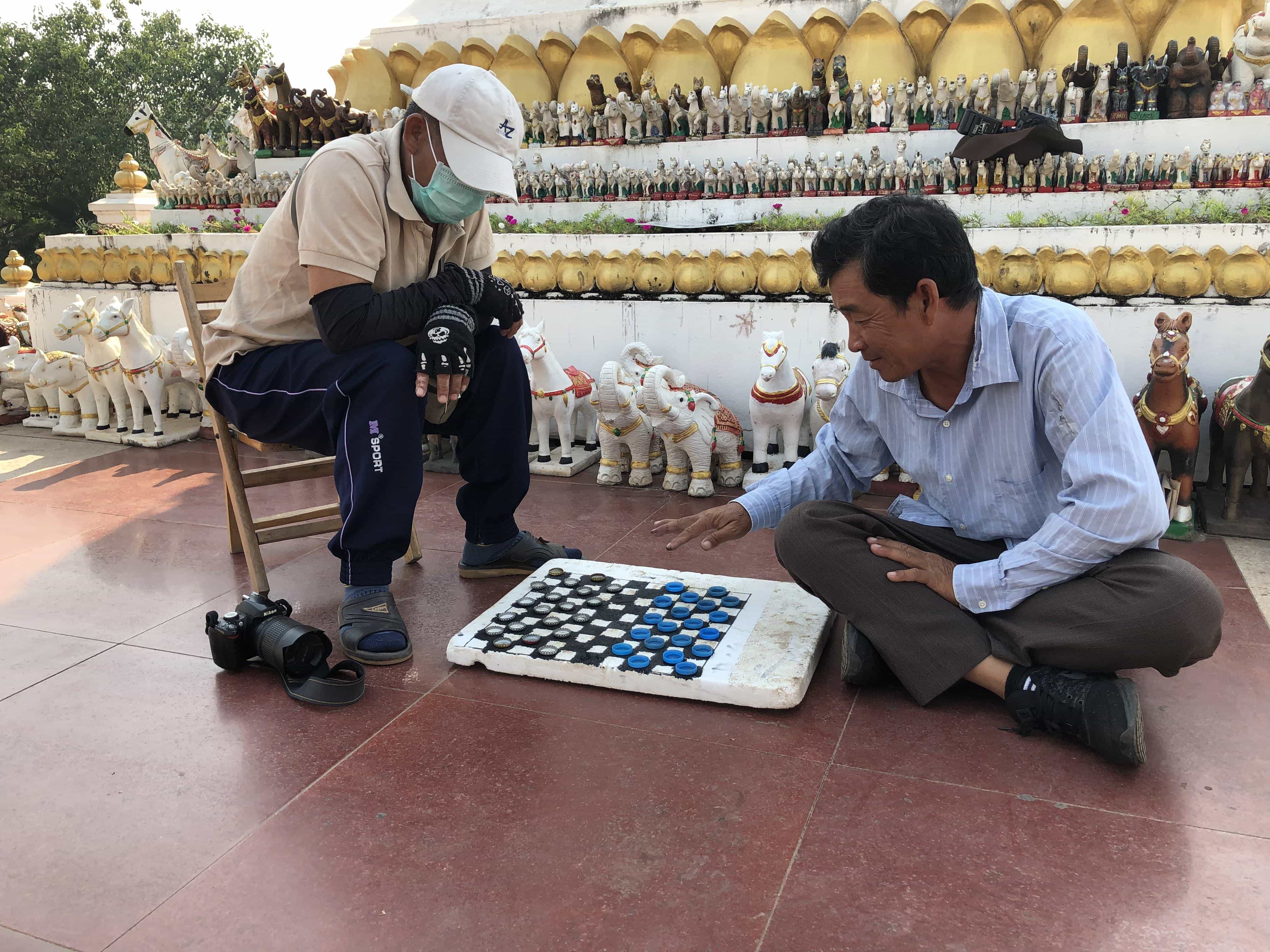 a couple of locals playing checkers with bottle caps
